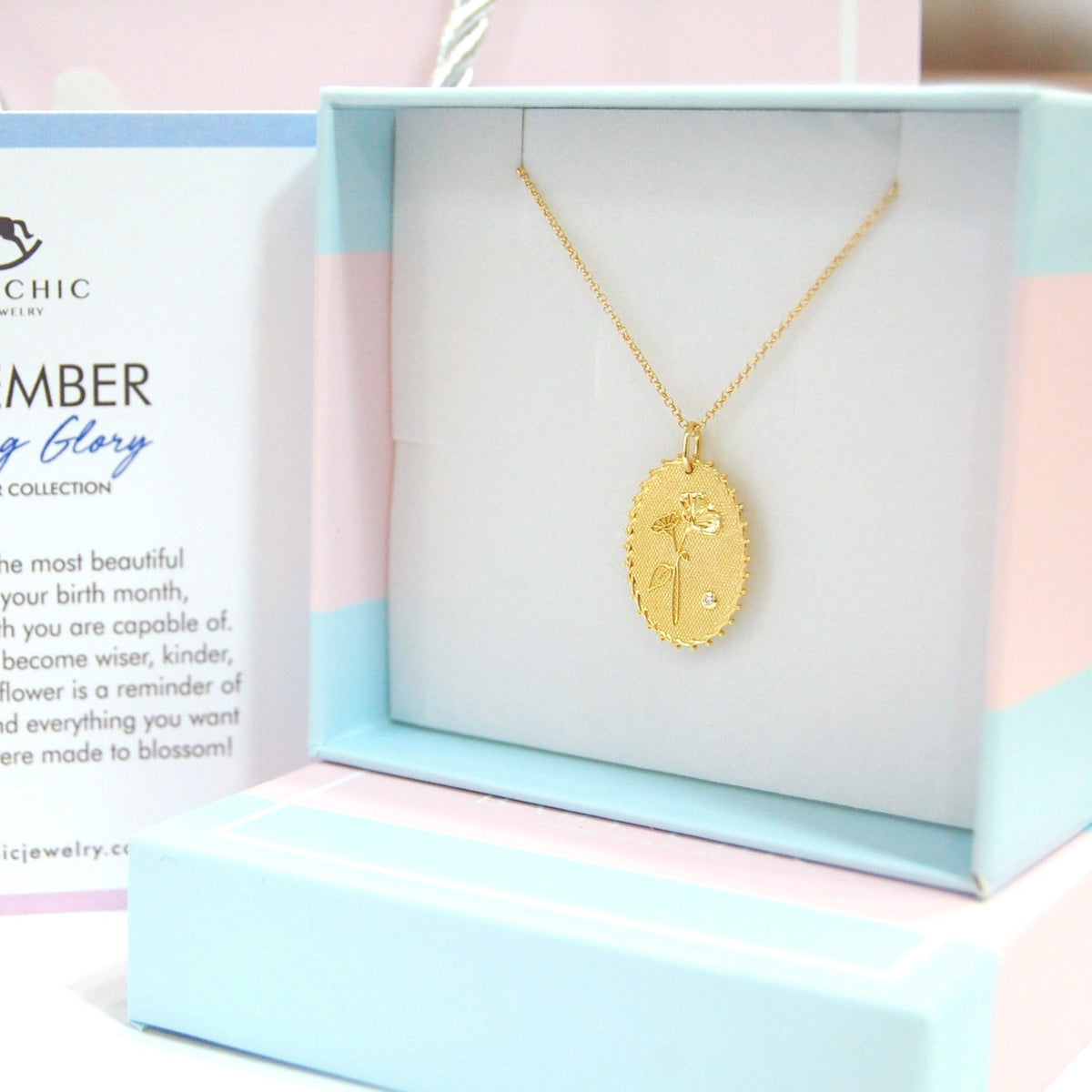 Gold necklace in a box with a card explaining the 'September Morning Glory' birth flower collection by Baby Chic.