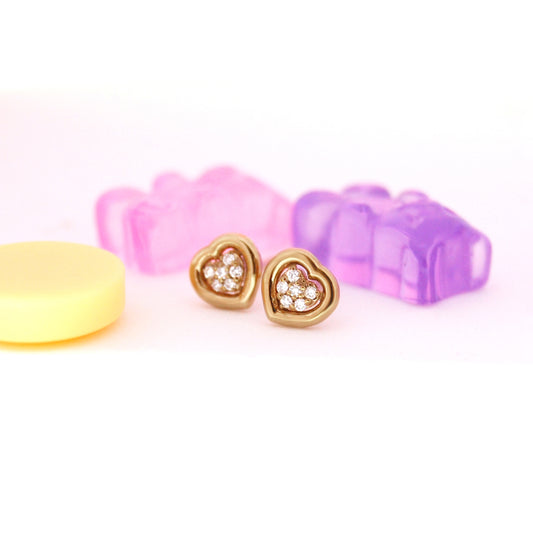 Heart-shaped gold earrings with clear stones on a white background