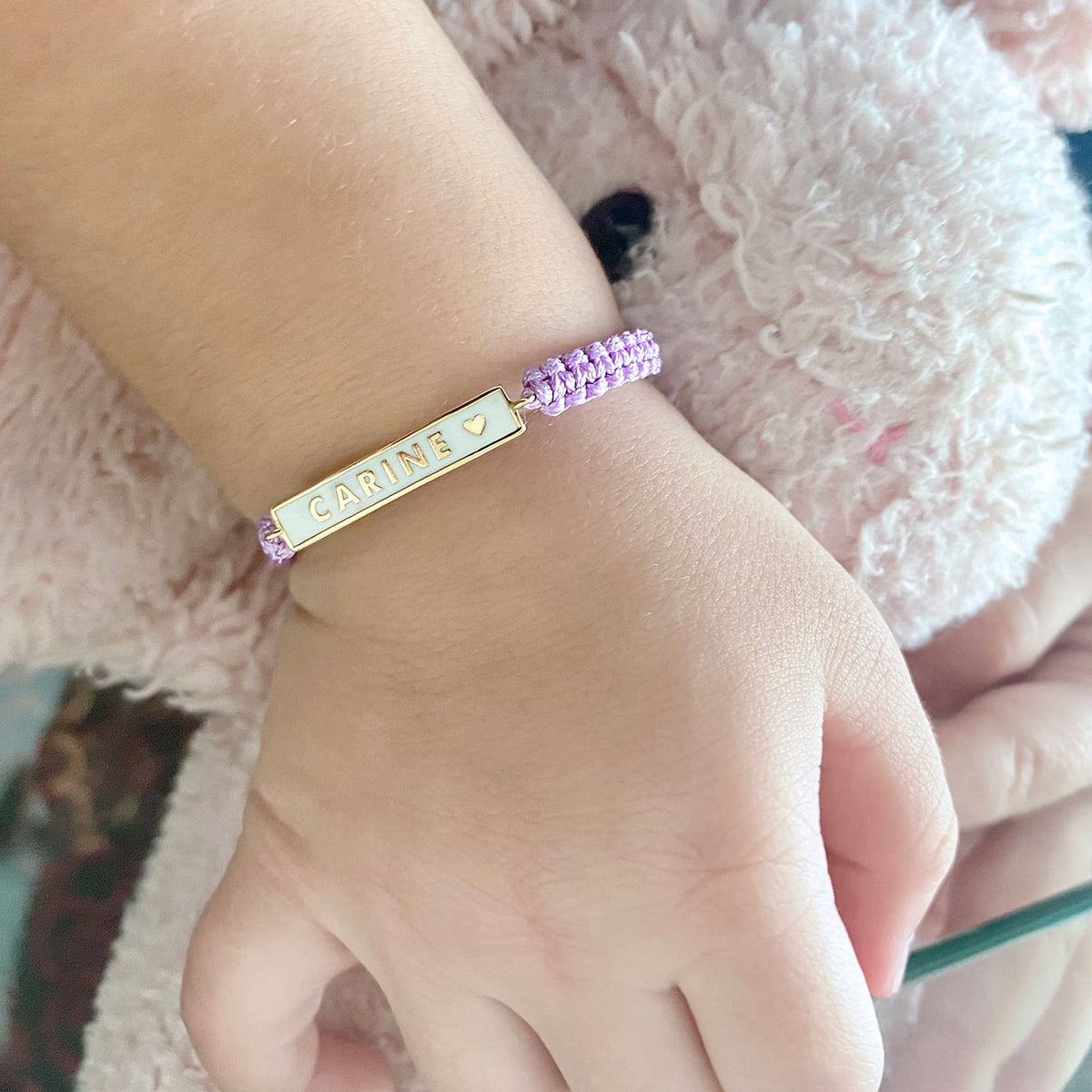Personalized name plate bracelet worn on wrist with purple cord