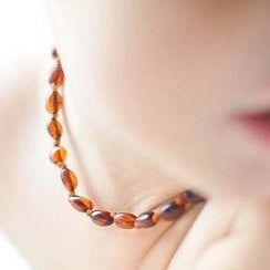 Amber baby necklace worn around neck with multicolor polished beads
