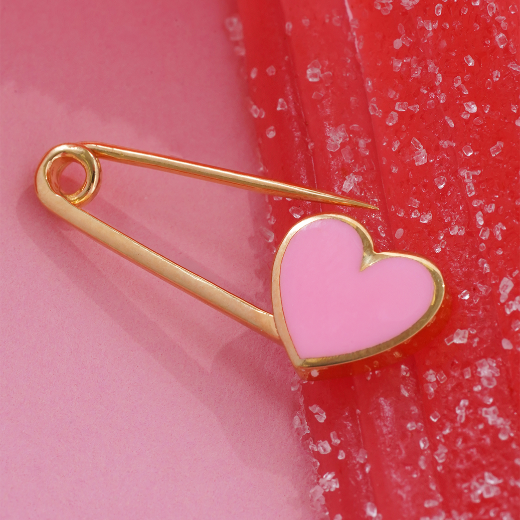 Heart-shaped brooch with gold outline on a pink and red background
