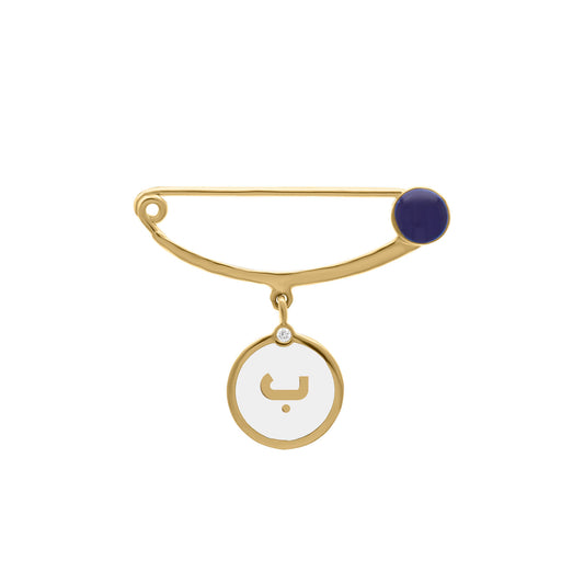 Gold safety pin brooch with navy enamel accent and a dangling round charm featuring the Arabic letter “ب” in gold and a small diamond detail.