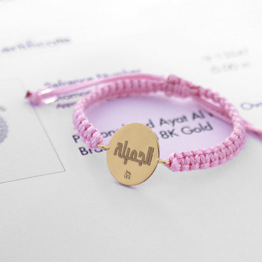 Pink cord bracelet with gold oval charm engraved with Arabic word جميلة