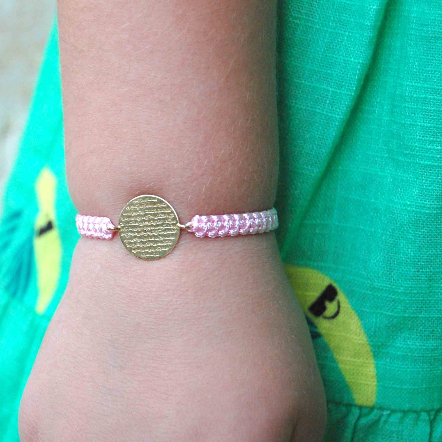 Child wearing pink Ayat Al Kursi bracelet with 18K gold oval charm