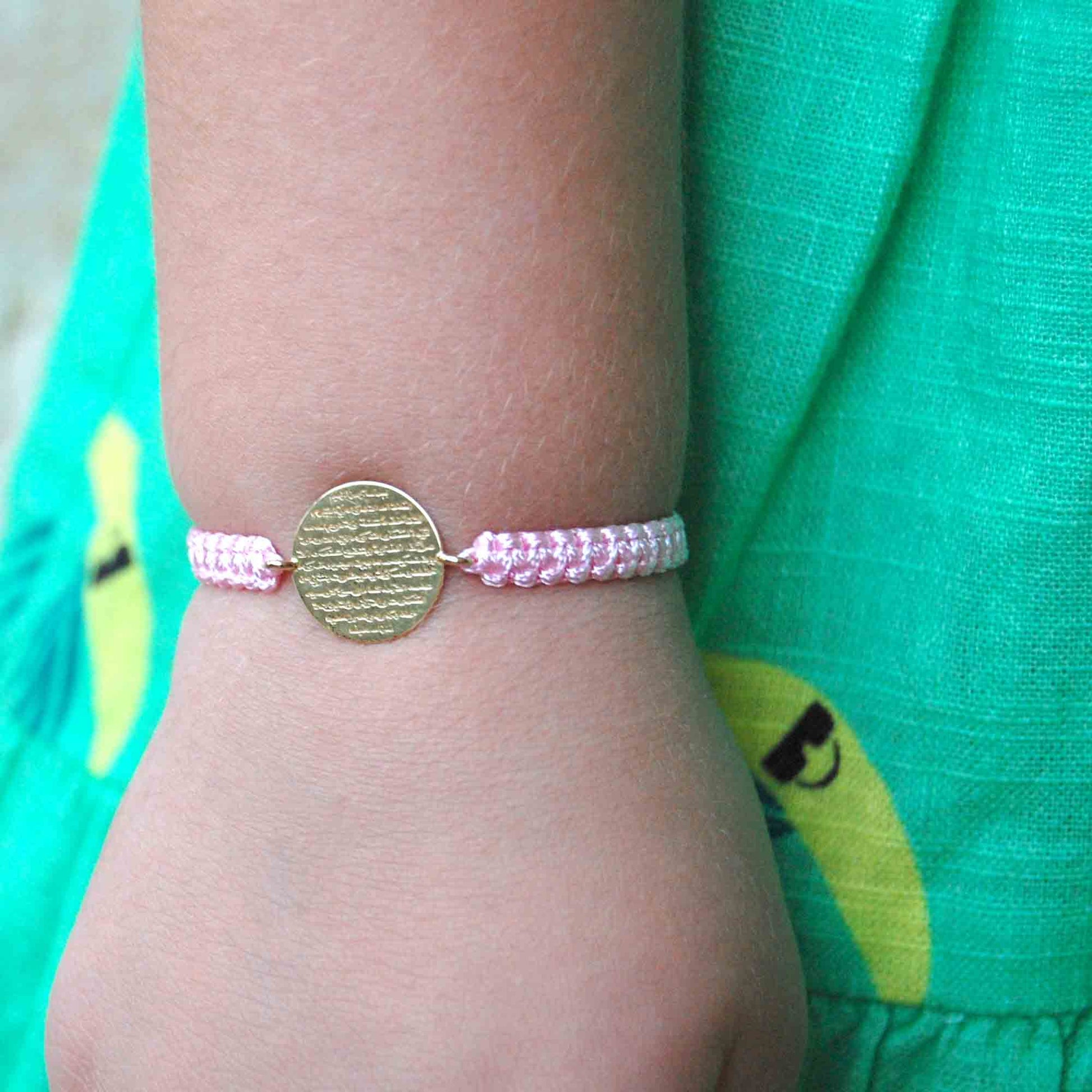 Child wearing pink Ayat Al Kursi bracelet with 18K gold oval charm