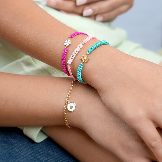 Colorful cord bracelets with gold charms and love name plate worn on wrist