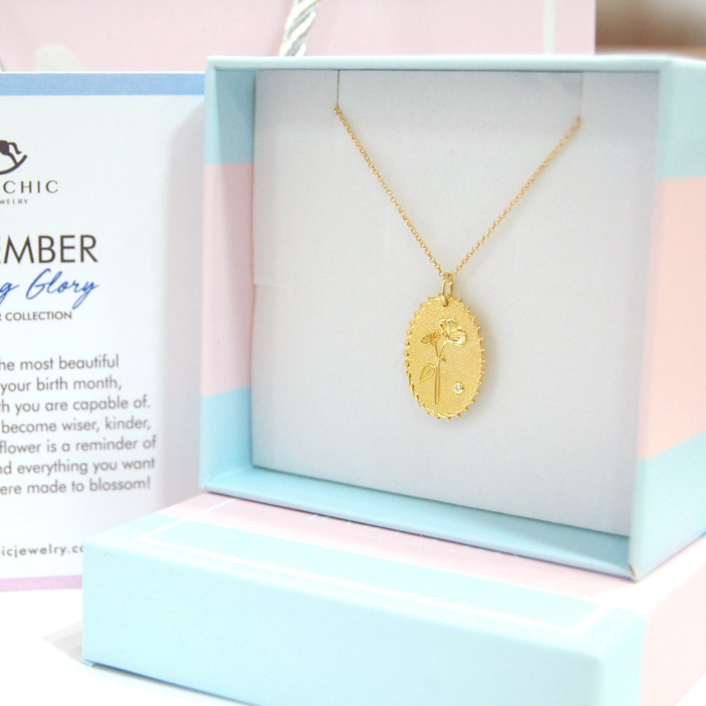 Gold necklace in a box with a card explaining the 'September Morning Glory' birth flower collection by Baby Chic.