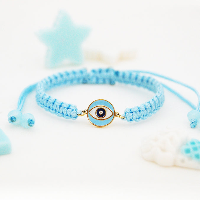 Adjustable blue macramé bracelet with a gold frame and an evil eye symbol in the center