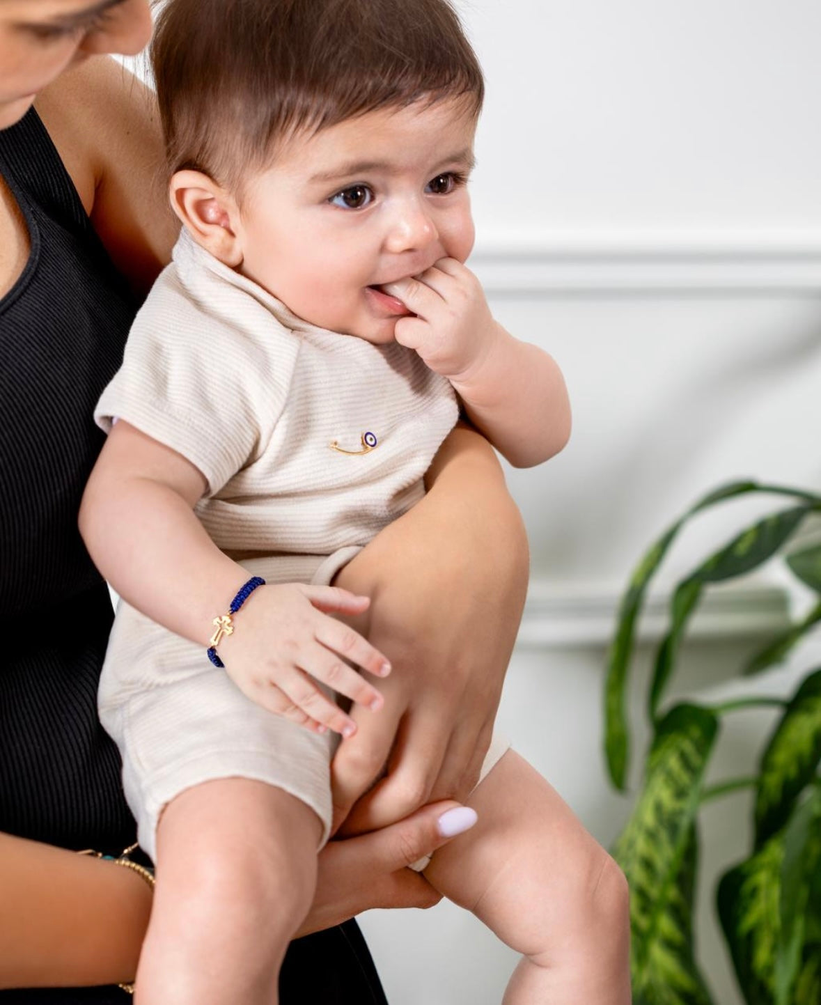 Baby wearing navy cord bracelet with gold cross charm