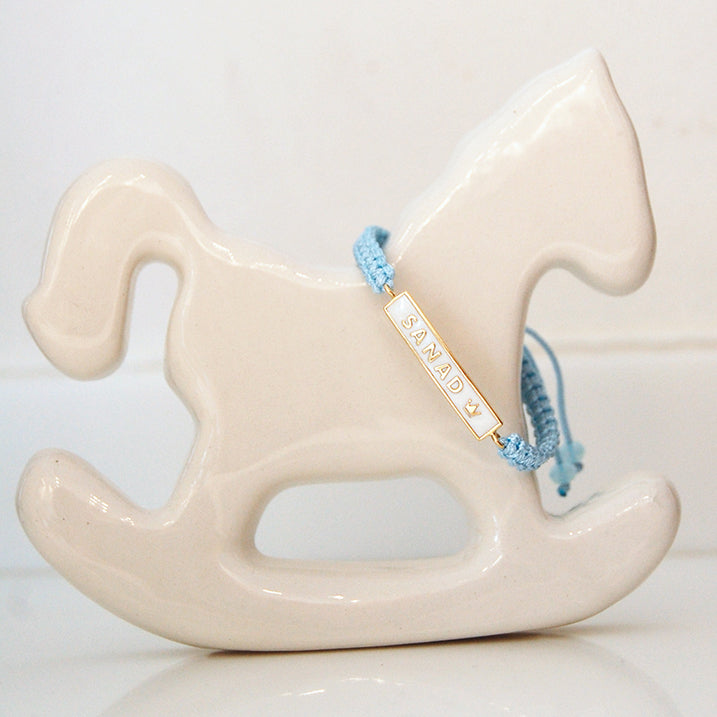 Custom name plate bracelet with blue cord displayed on stand