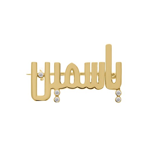 Gold brooch featuring a custom Arabic name design adorned with multiple round diamond accents hanging below, displayed on a transparent background.