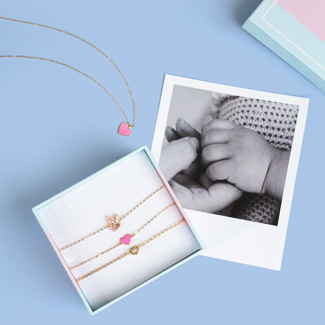 Baby jewelry gift set with gold necklaces and heart bracelet displayed in box