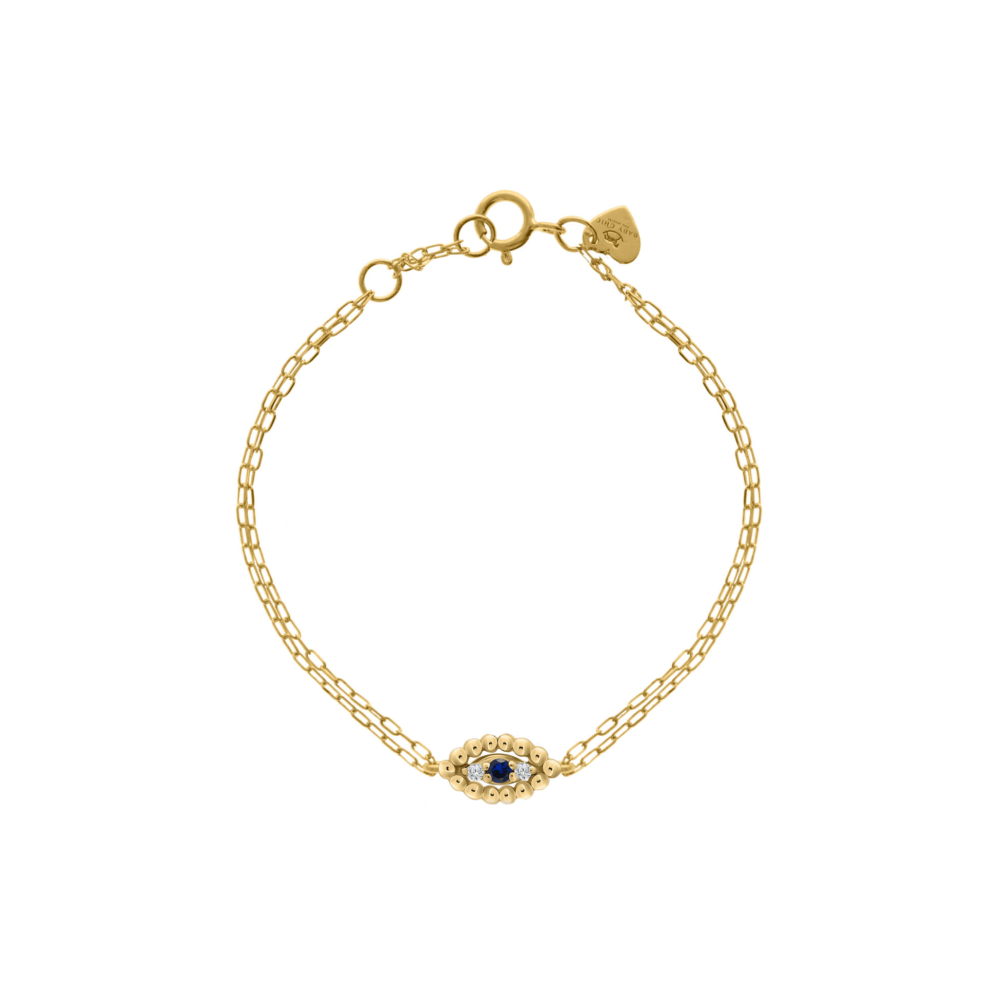Studio shot of an 18K yellow-gold evil-eye bracelet: a central eye-shaped motif of tiny gold beads encircling a blue sapphire and two small round diamonds, suspended on a delicate chain with a spring-ring clasp and a heart-shaped brand tag, shown on a transparent background.