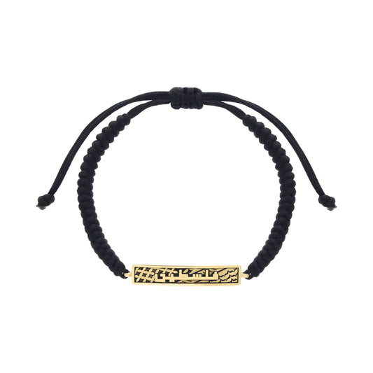 Black adjustable cord bracelet with a rectangular gold plate engraved in Arabic calligraphy reading “فلسطين” (Falasteen), meaning Palestine.