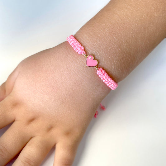Close-up of a child’s wrist wearing the pink macrame Forever Love Diamond Bracelet with a heart charm and diamond accent.
