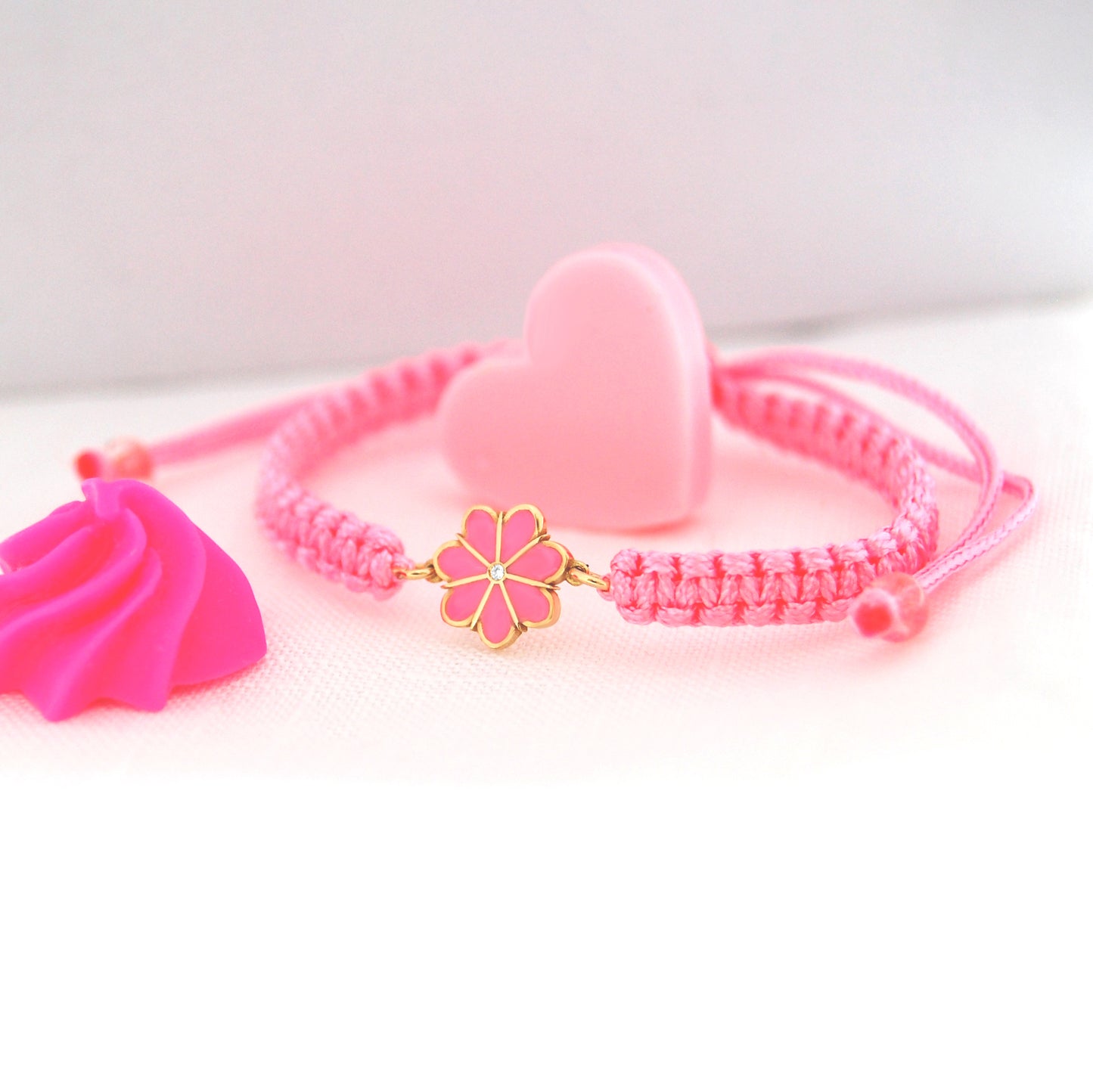 Pink bracelet with gold charm on a white background