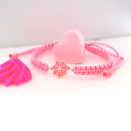 Pink bracelet with gold charm on a white background