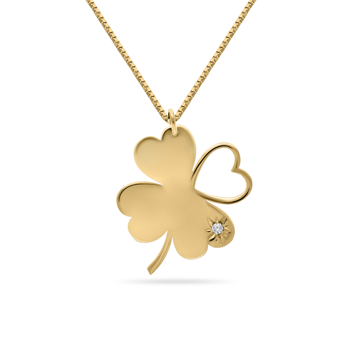 A studio shot of an 18K yellow-gold ‘Piece of My Heart’ necklace on a transparent background: a clover-shaped pendant formed by three solid heart-shaped leaves and one open-heart leaf, accented with a starburst motif and single round brilliant-cut diamond on one petal, suspended from a fine paper-clip chain.