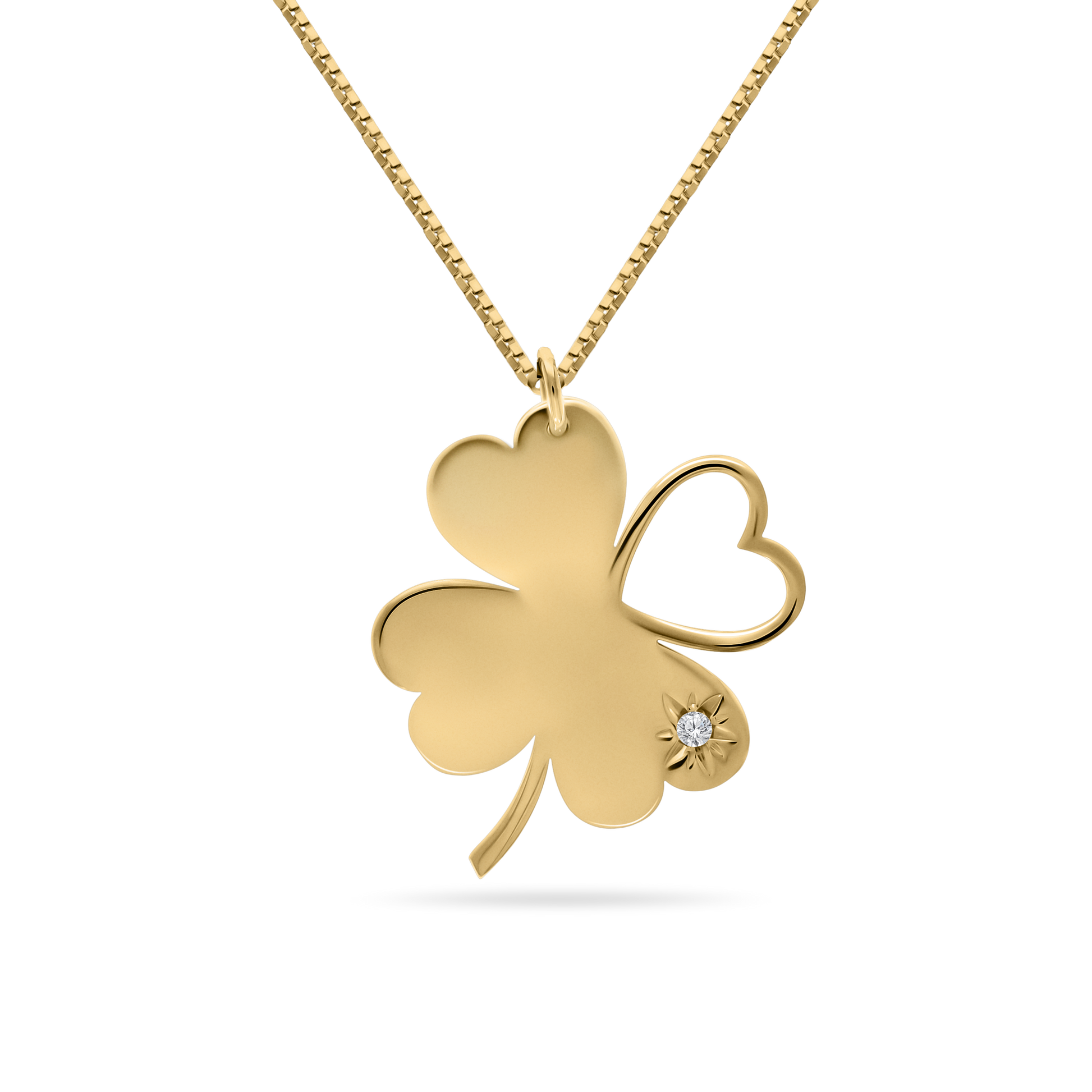 A studio shot of an 18K yellow-gold ‘Piece of My Heart’ necklace on a transparent background: a clover-shaped pendant formed by three solid heart-shaped leaves and one open-heart leaf, accented with a starburst motif and single round brilliant-cut diamond on one petal, suspended from a fine paper-clip chain.