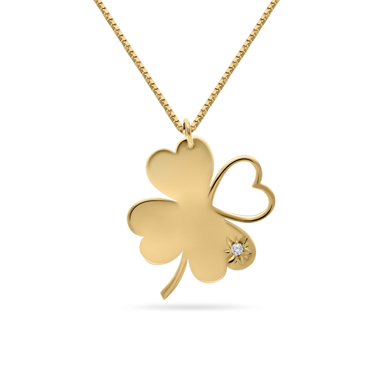 A studio shot of an 18K yellow-gold ‘Piece of My Heart’ necklace on a transparent background: a clover-shaped pendant formed by three solid heart-shaped leaves and one open-heart leaf, accented with a starburst motif and single round brilliant-cut diamond on one petal, suspended from a fine paper-clip chain.