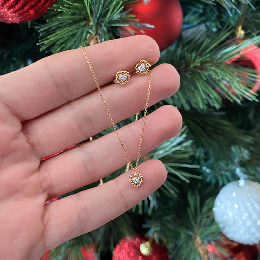 Hand holding the Sweetest of Hearts Diamond Earrings and matching necklace by BabyChic Jewelry, set against a festive Christmas tree background.