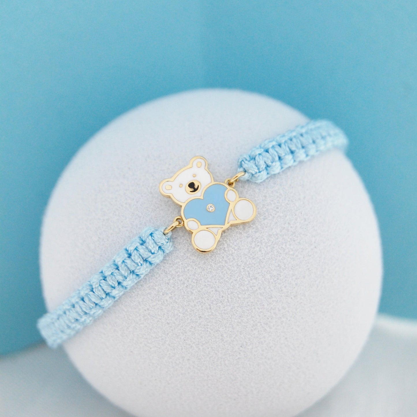 Close up of blue cord bracelet with teddy bear heart charm