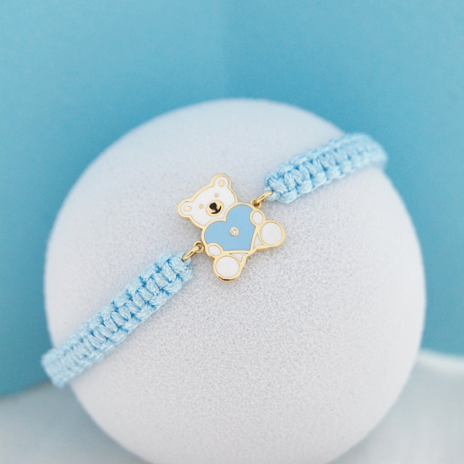 Close up of blue cord bracelet with teddy bear heart charm