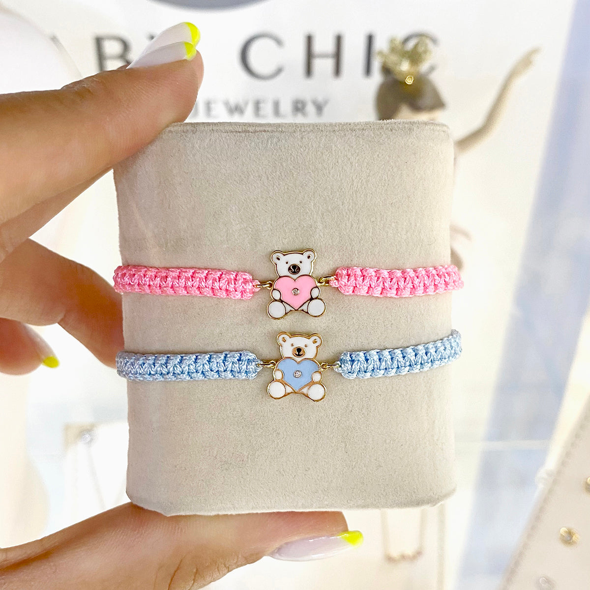 Pink and blue cord bracelets with teddy bear heart charms displayed