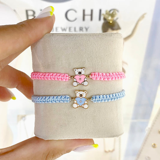 Pink and blue cord bracelets with teddy bear heart charms displayed